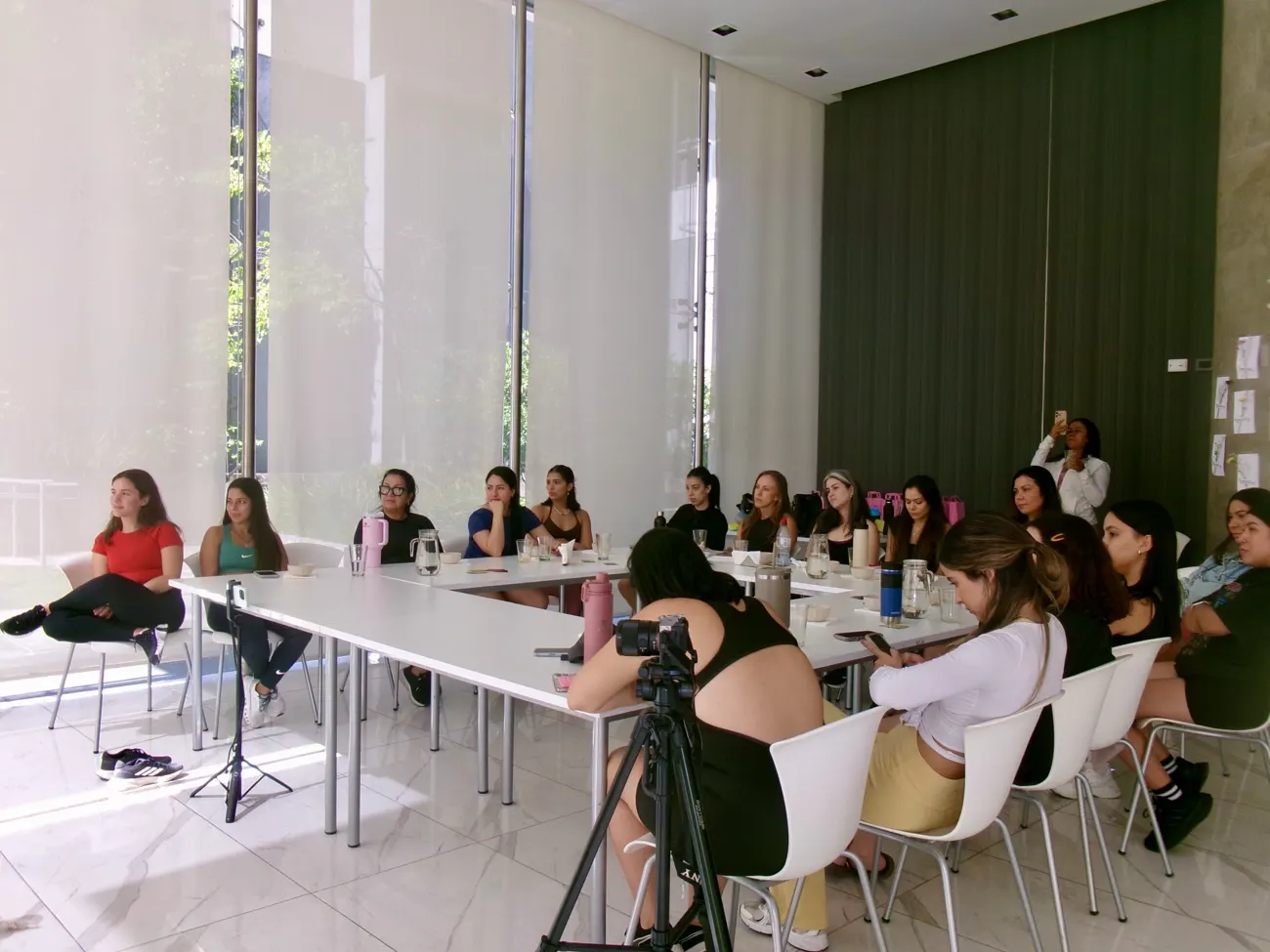 Participantes sentadas en mesa en U escuchando una charla