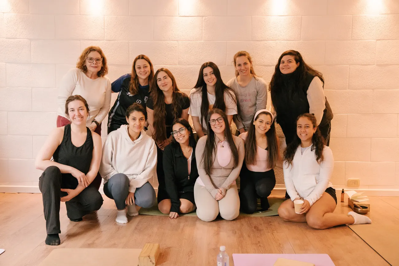 Grupo de participantes en un estudio de yoga con paredes de ladrillo blanco