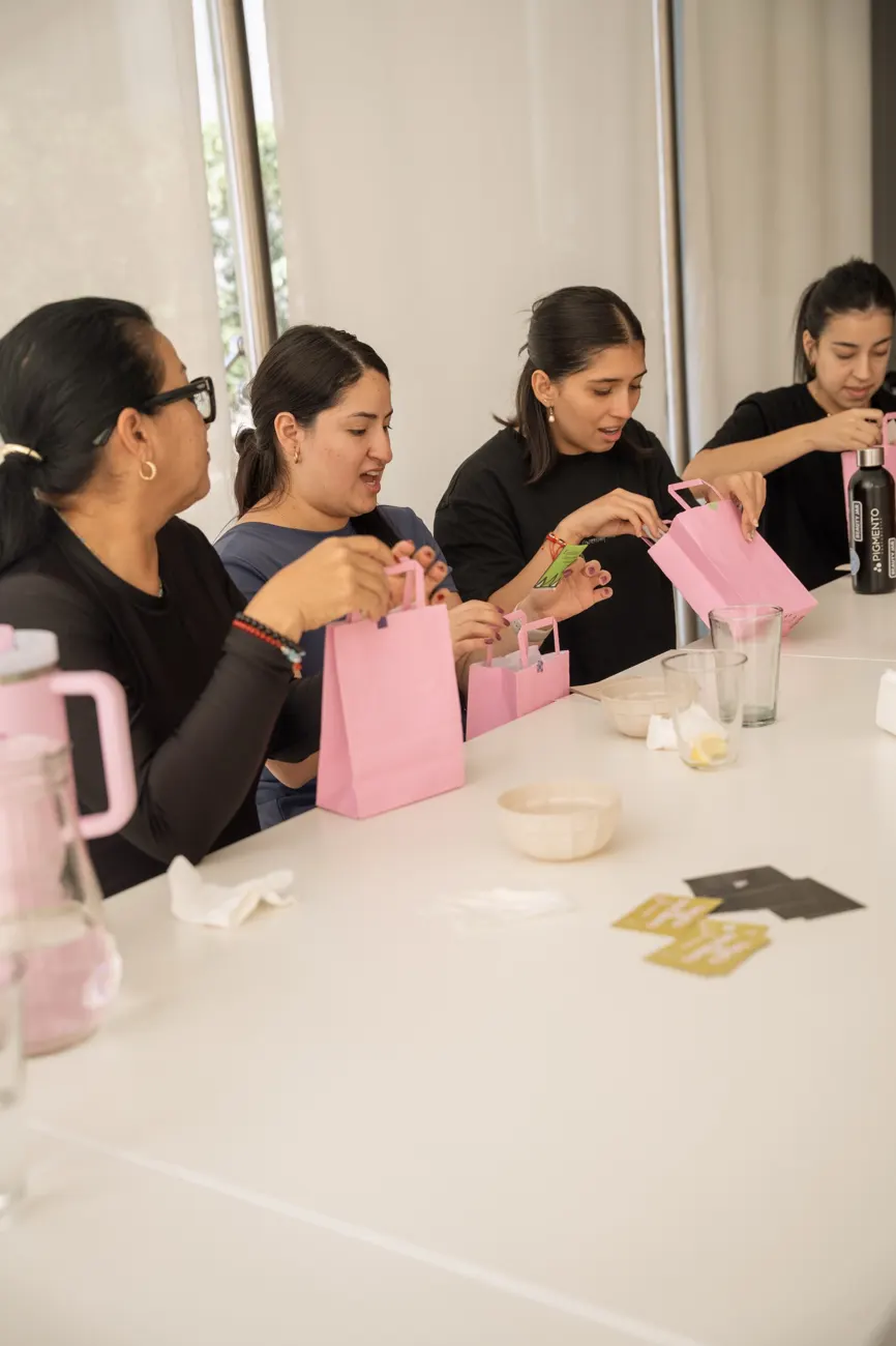 Participantes abriendo bolsas rosas con productos de regalo